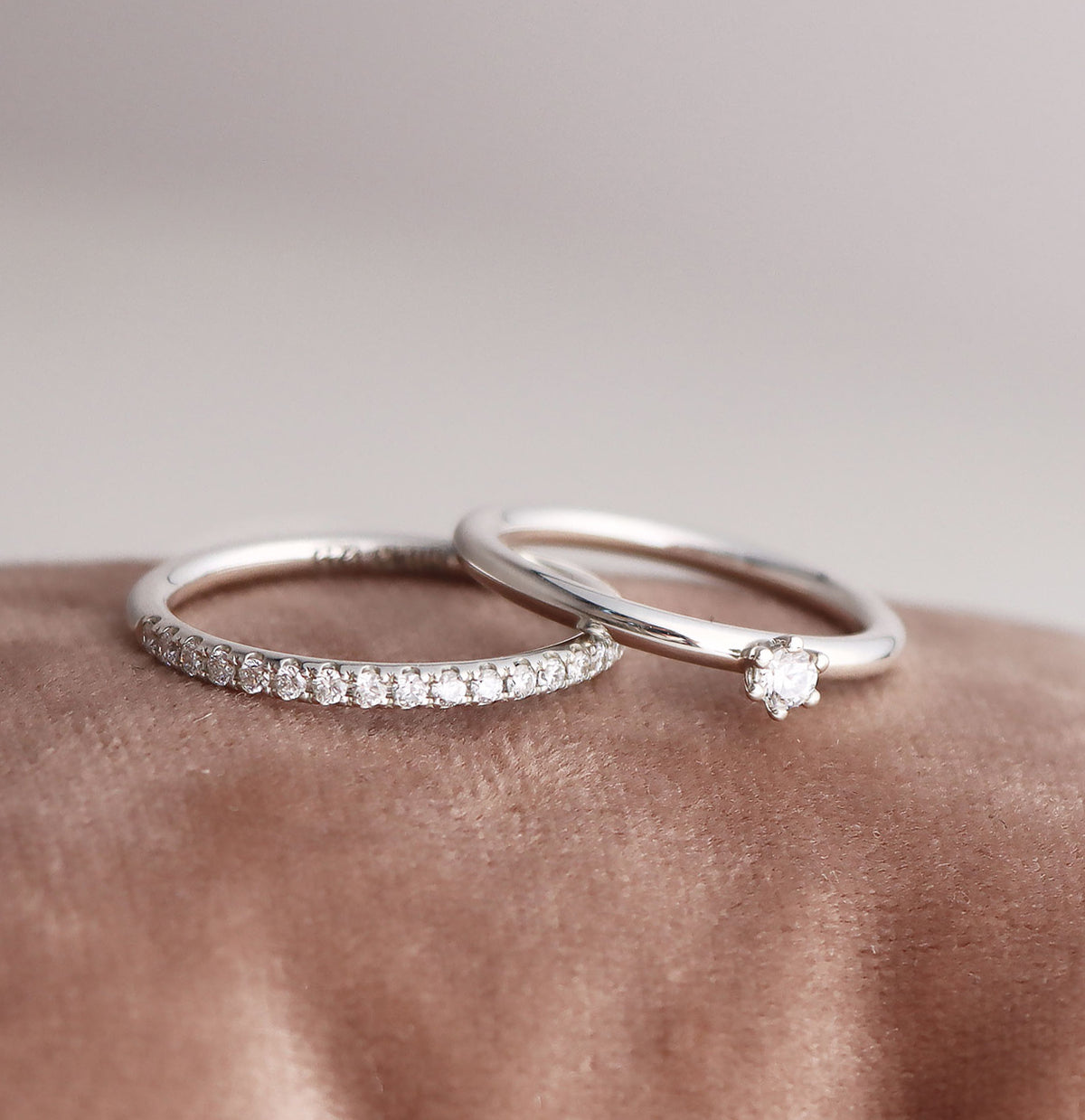 Ring par med vigselring och förlovningsring. Silverringar med diamanter, placerade på ett sammetstyg.