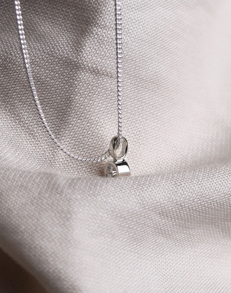 Hängsmycke med diamant i rörfattning sett från sidan.