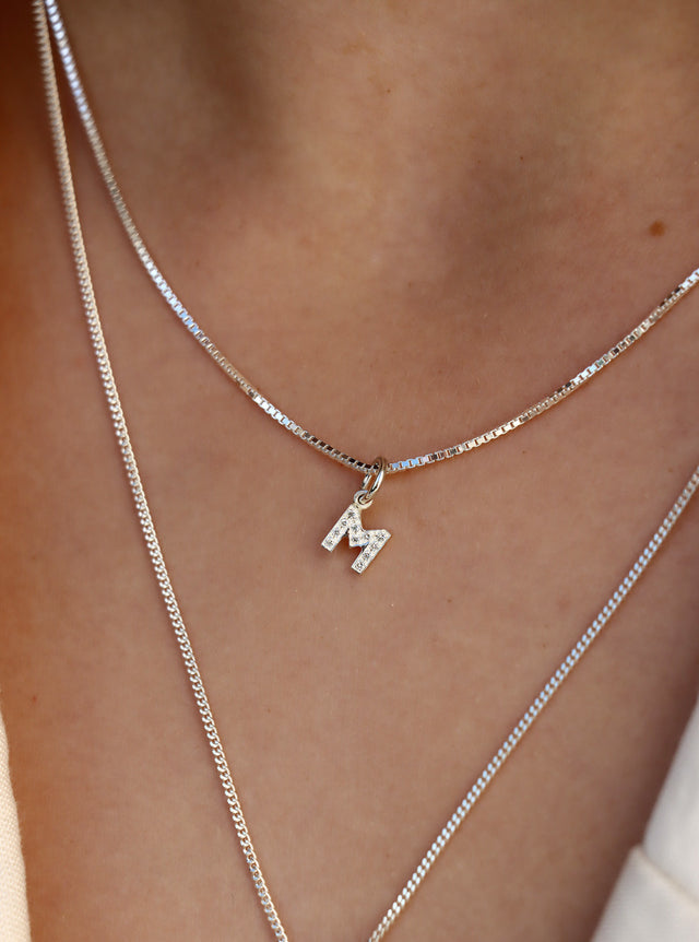 Halsband med bokstavsberlock i silver med diamanter.
