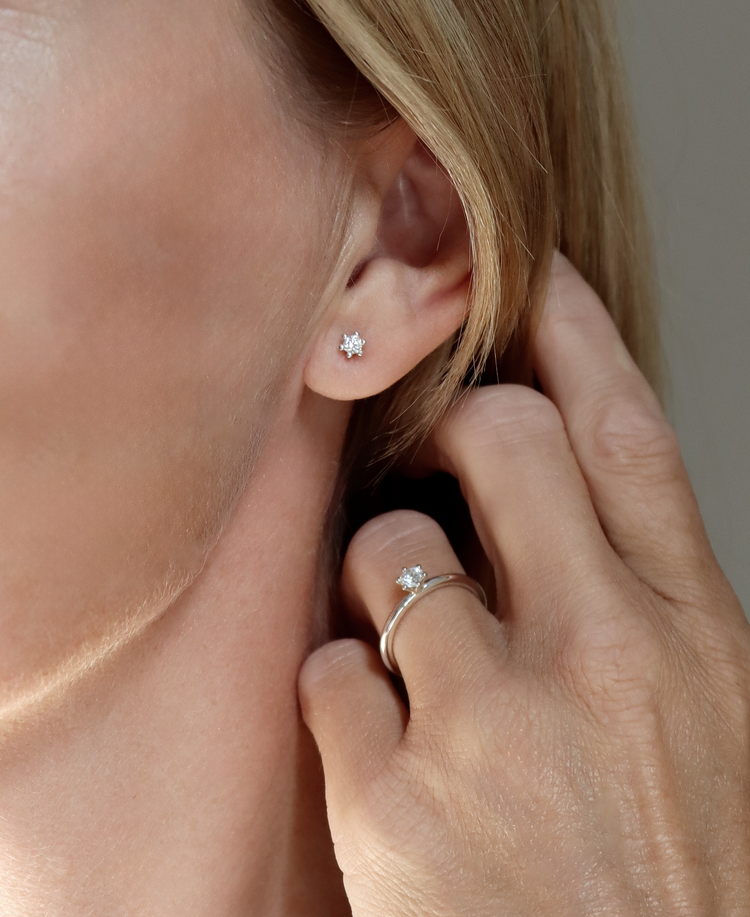 Tjej som bär små diamantörhängen med matchande diamantring.