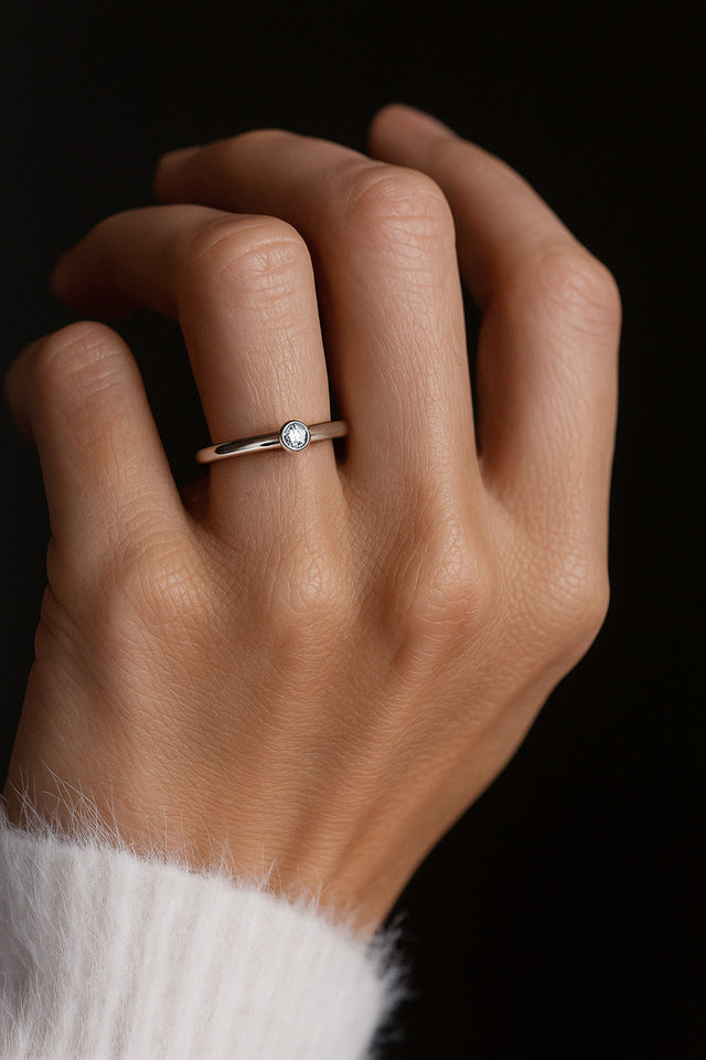 Diamantring i silver som bärs på ringfingret. Diamanten är infattad i tub-fattning.