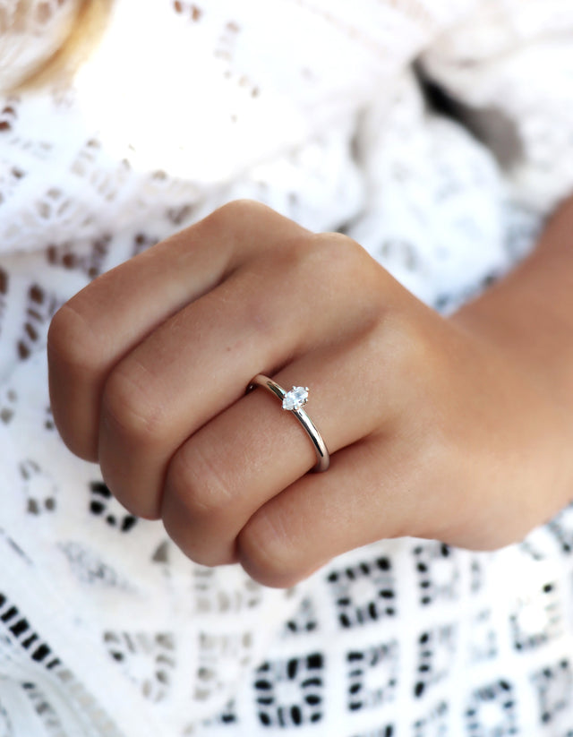 Tjej som bär en diamantring i silver med oval diamant som vigsel eller förlovningsring.