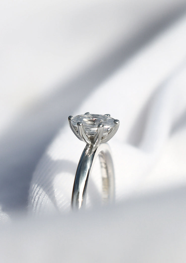 Diamantring med oval diamant sedd från sidan med 6-klo fattning.