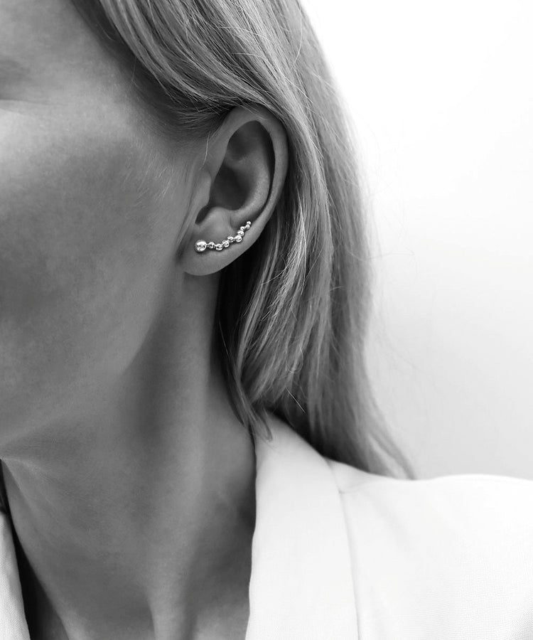 Tjej som bär ett örhänge som klättrar längs örat.