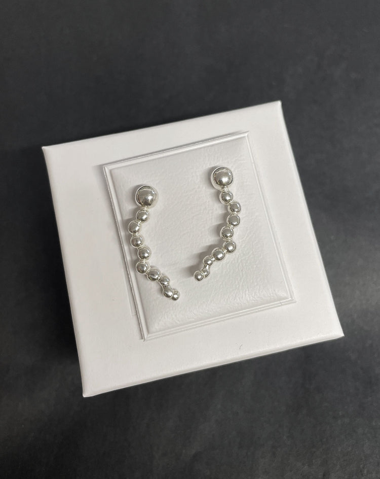 Örhängen med små silverkulor formade som ett stjärnfall.