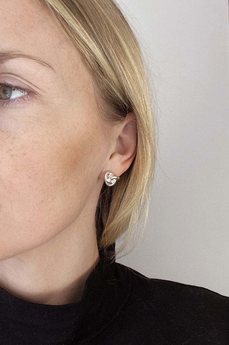 Tjej som bär örhängen med knutar i silver.