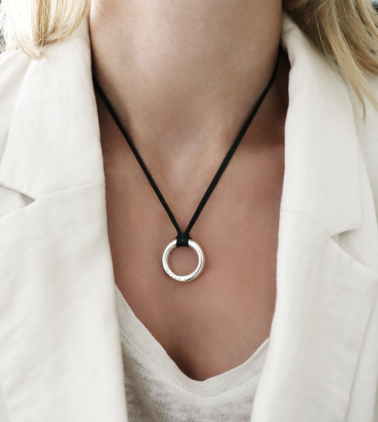 Tjej som bär ett halsband med en graverad ring i svart läderband.