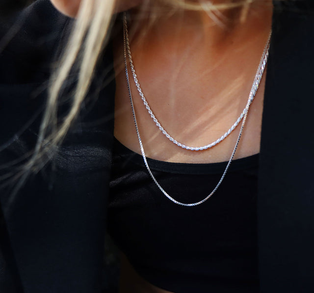 Tjej som bär lager med silverkedjor som halsband