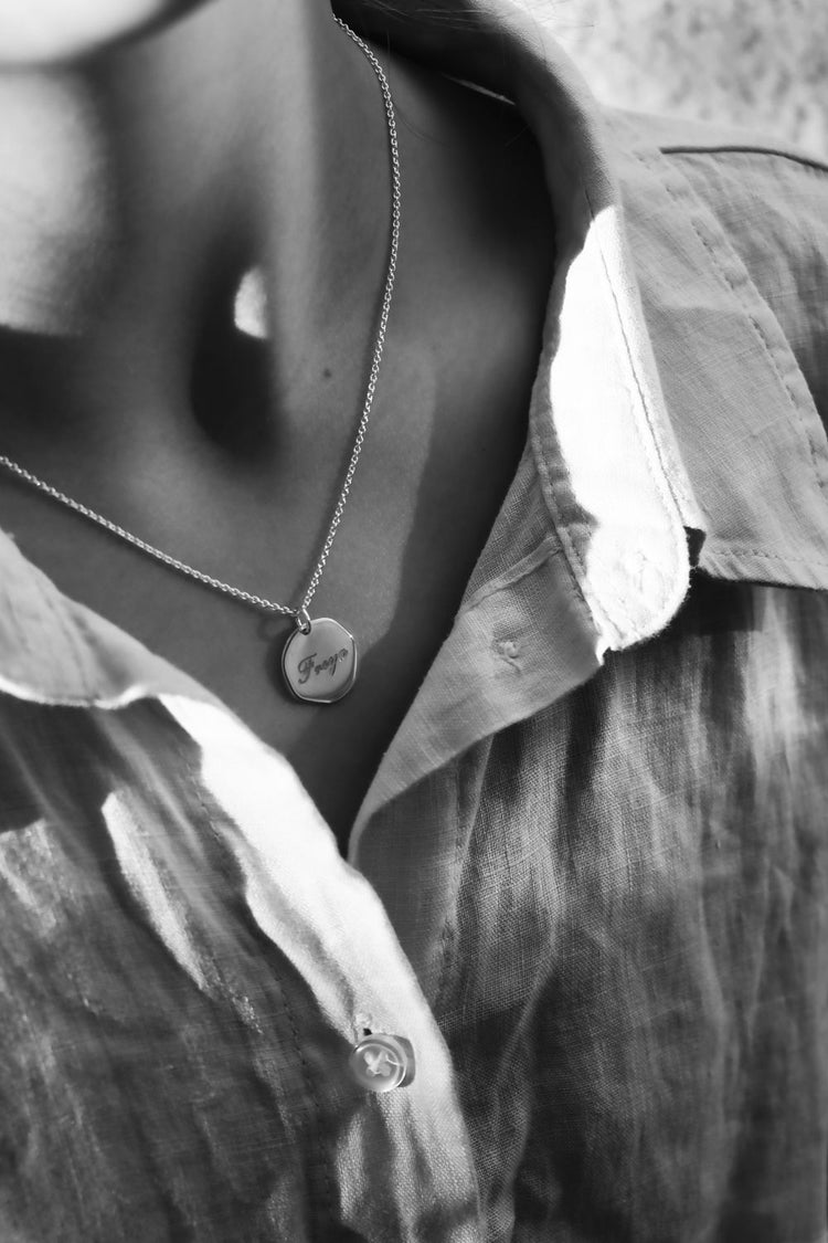 tjej som bär ett halsband med silverberlock som har graverat namn i skrivstil.