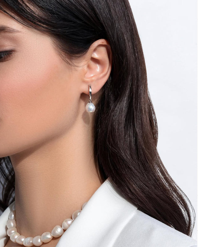 tjej som bär pärlörhänge med ring i silver och hängande pärla.