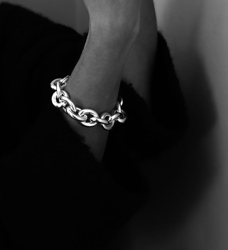 Svart-vit bild med ett stort kedjearmband i silver med ovala länkar.