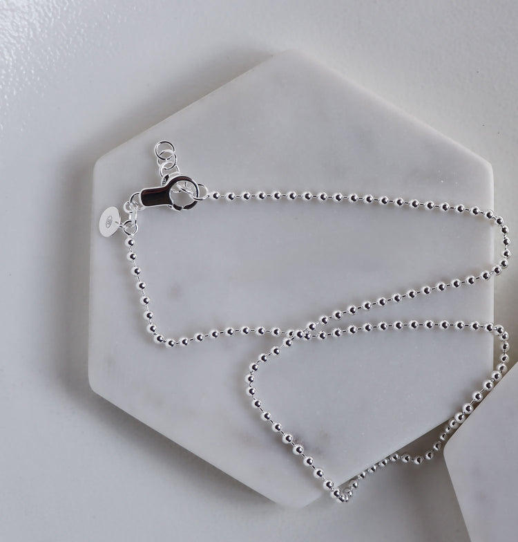 Närbild på lås och förlängningsöglor på en kulkedja i silver.