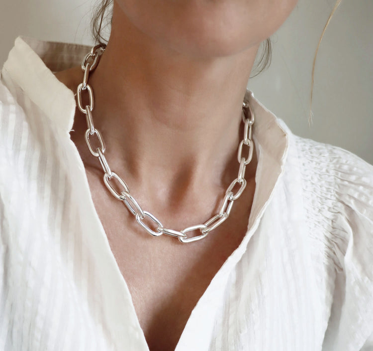 Tjej som bär ett stort silverhalsband med kedja.