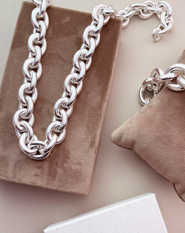 En stor silverkedja med blanka runda silverlänkar som ligger på ett sammetsblock.