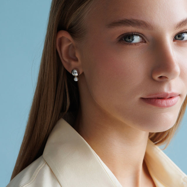 Tjej som bär örhängen med silverkulor och vita sötvattenspärlor.