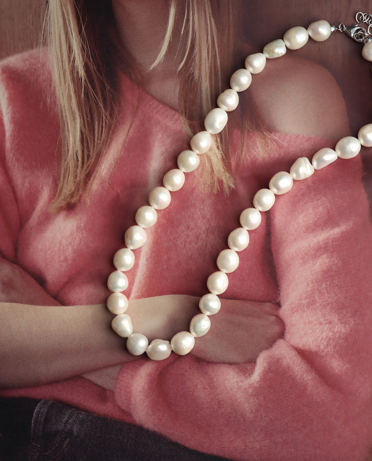 halsband med stora pärlor som har barock-form. ligger på ett magasin.