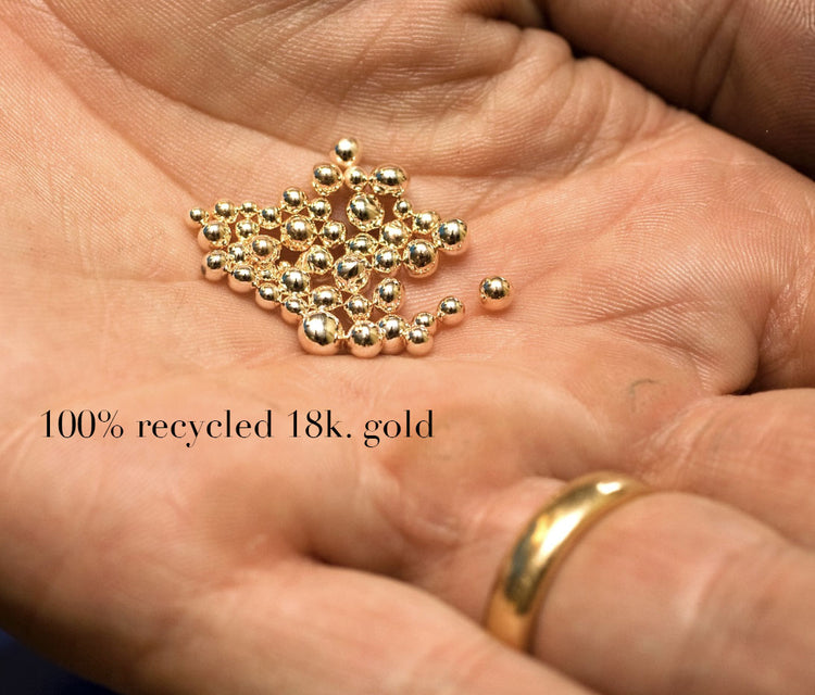 Små kulor av återvunnet guld i handflata