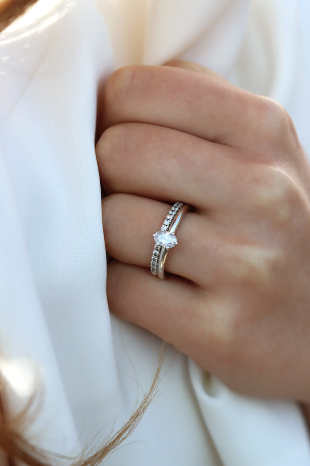 Kvinna som bär ett set med vigsel och förlovningsring med alliansring och ring med oval diamant.