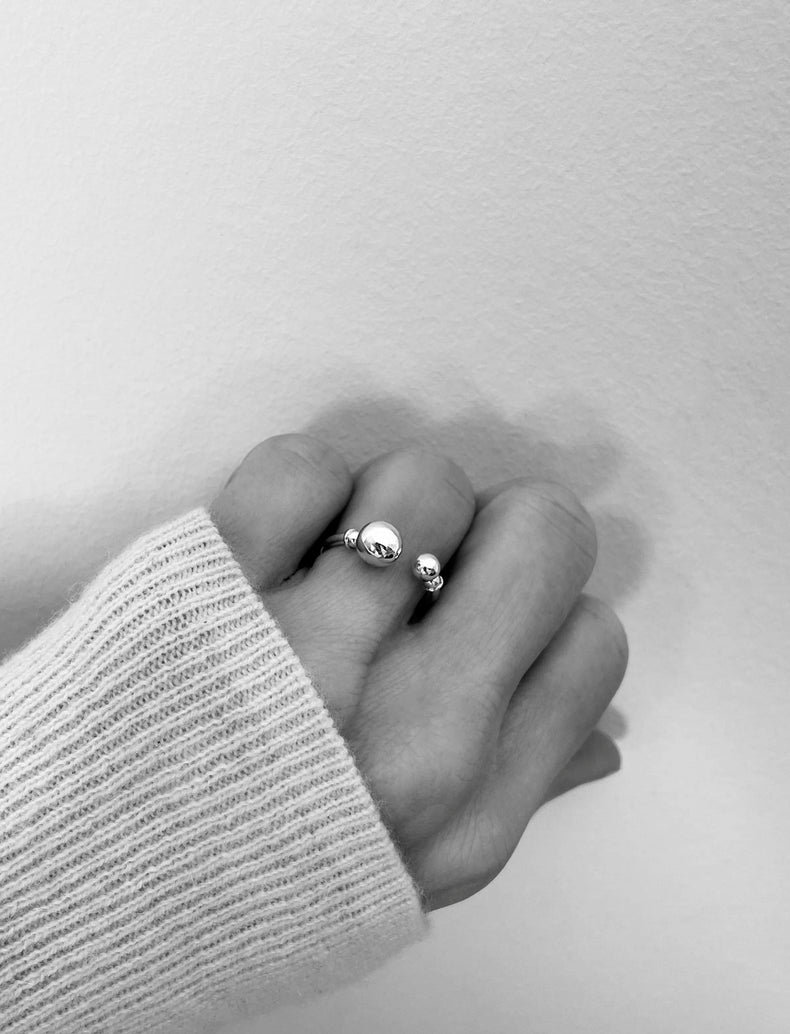 Silverring som är öppen fram med två kulor i olika storlekar.