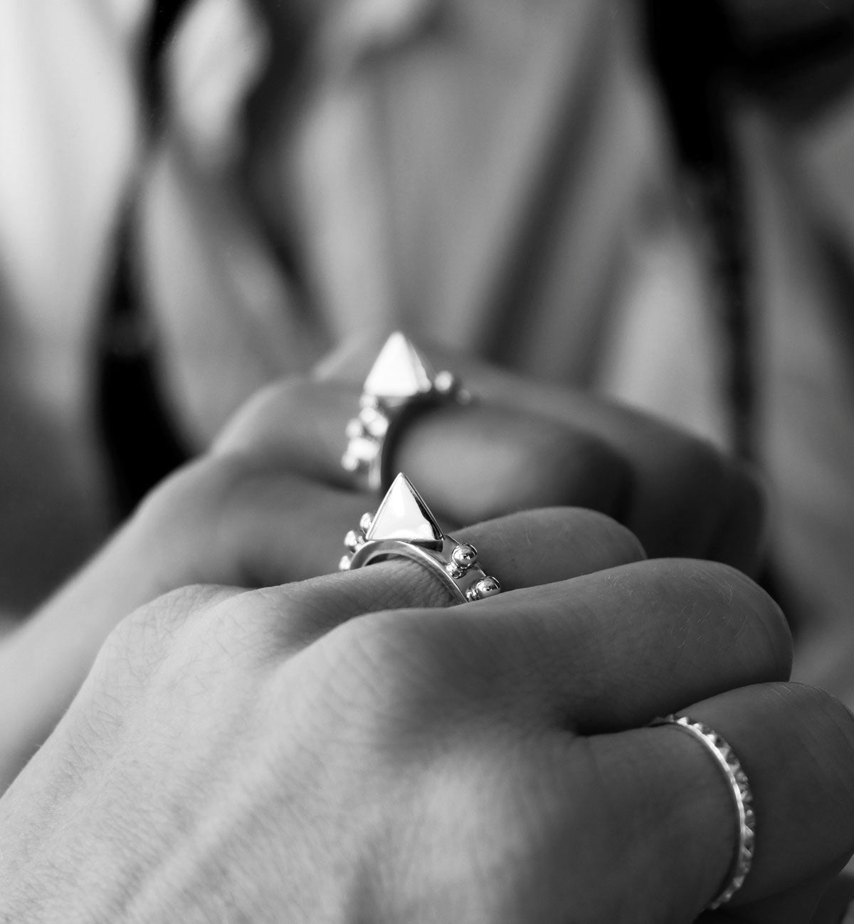 Silverring med en spets som bÀrs pÄ ett ringfingret, pÄ ringringret bÀr en smal silverring med slipat mönster.