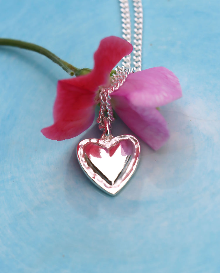 silverhalsband med silverkedja i pansarkedja placerad på en blomma.