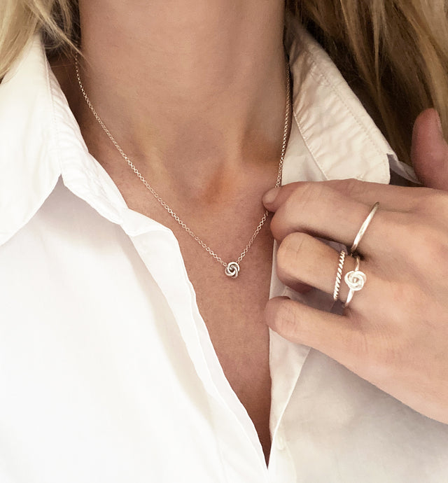 Tjej som bär ett kort silverhalsband med knut.