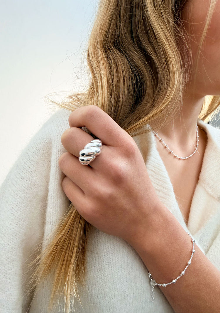 Tjej som bär en stor bullig silverring på långfingret.