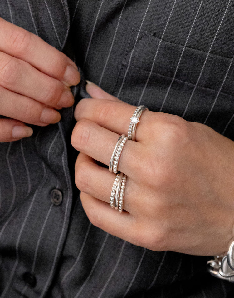 Tjej som bär flera smala silverringar och diamantringar på olika fingrar. Äkta silverringar i olika design.