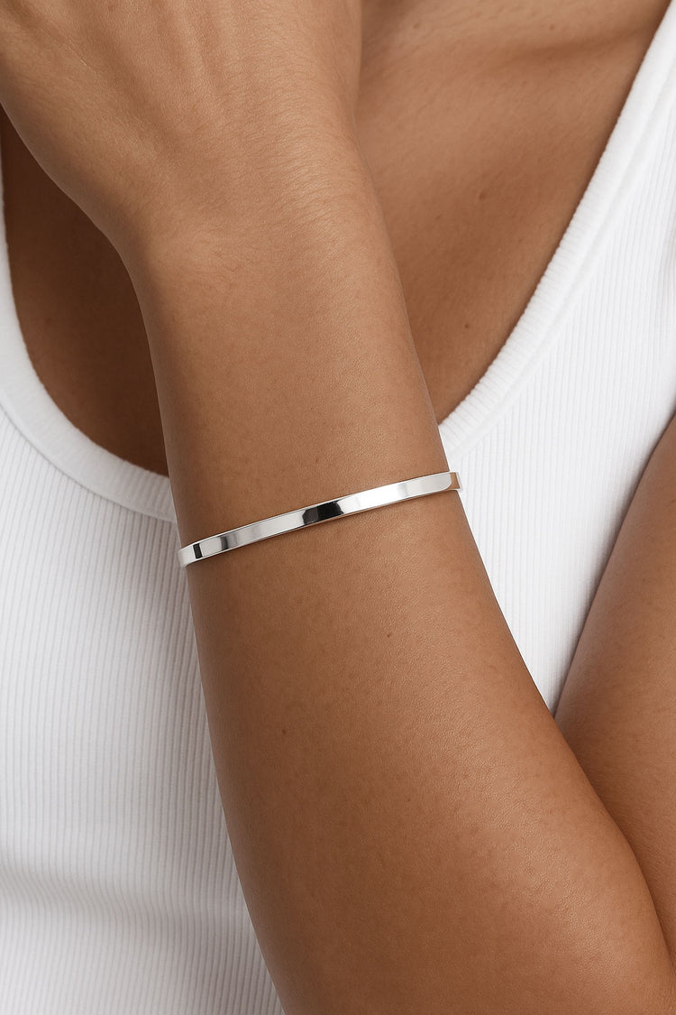 Tjej som bär ett smalt stelt silverarmband med fin glans