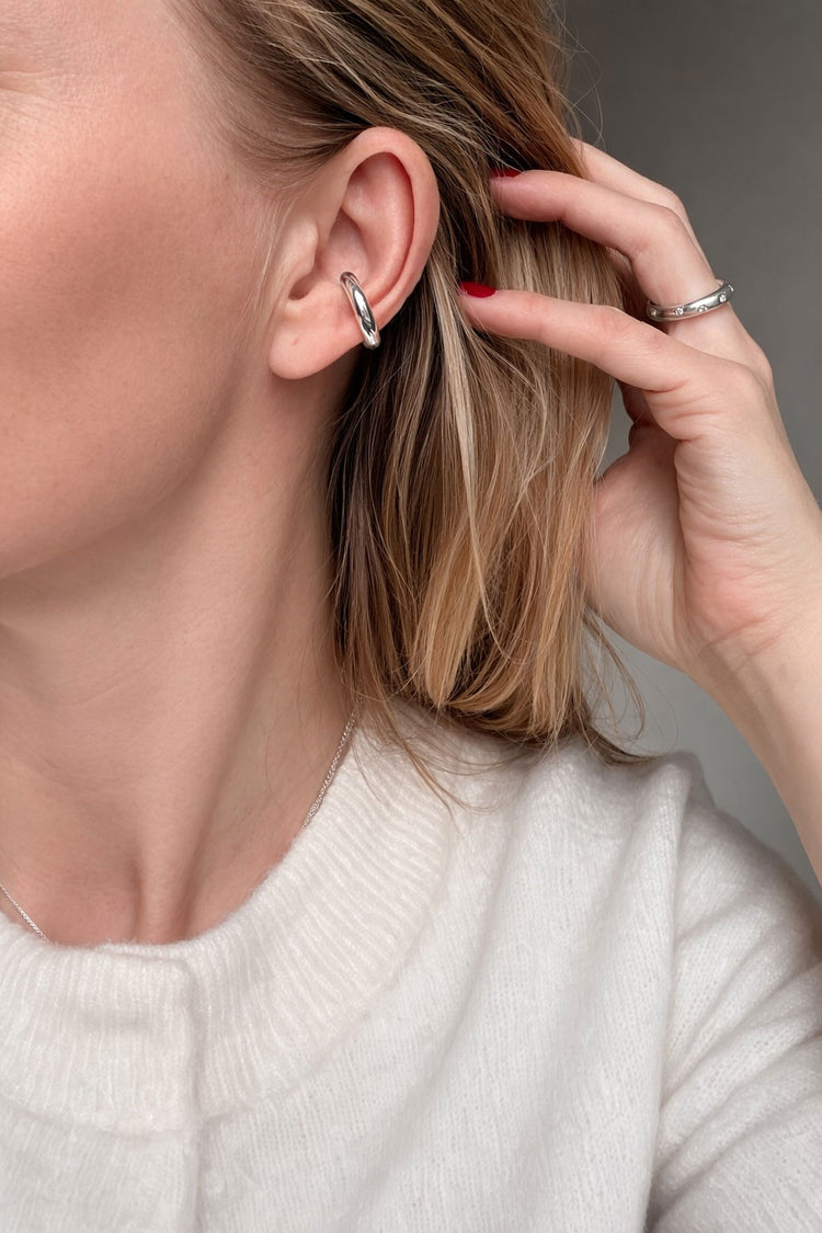 tjej som bär en silver ear cuff en bit ned på örat med matchande silverring.