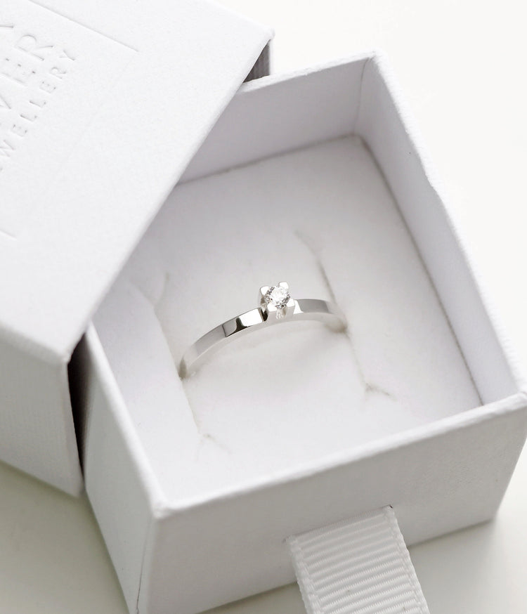 Silverring med 0,10 ct diamant placerad i en vit ringask.