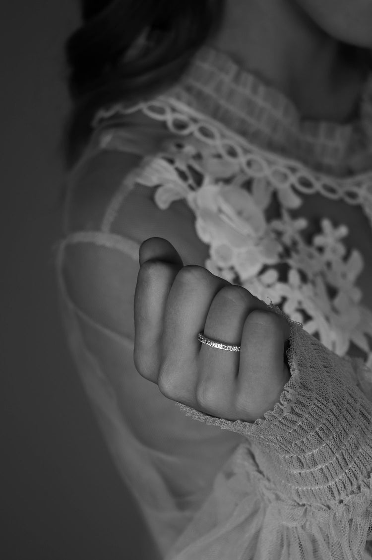 Tjej som bär en vigsel eller förlovningsring med ett band av vita diamanter.