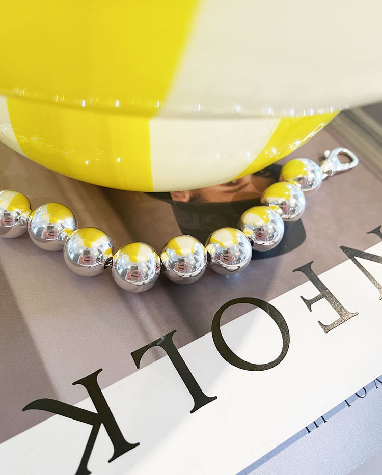 Armband med stora silverkulor placerade på ett magasin.