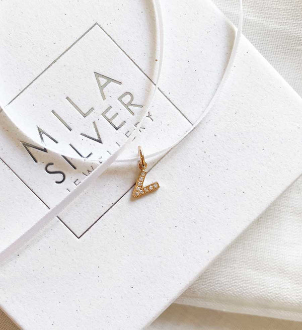 Diamantbokstav i guld placerad på en ask från Mila Silver.