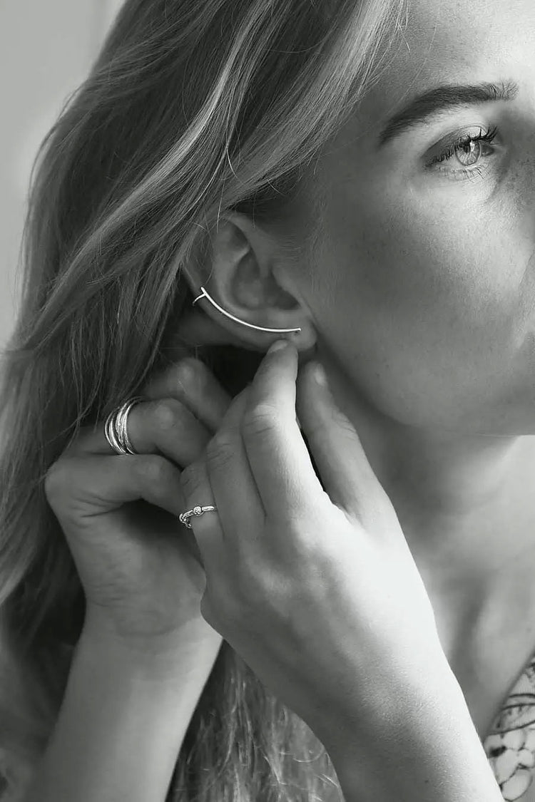Tjej som tar på sig ett långt silverörhänge som följer örats form.