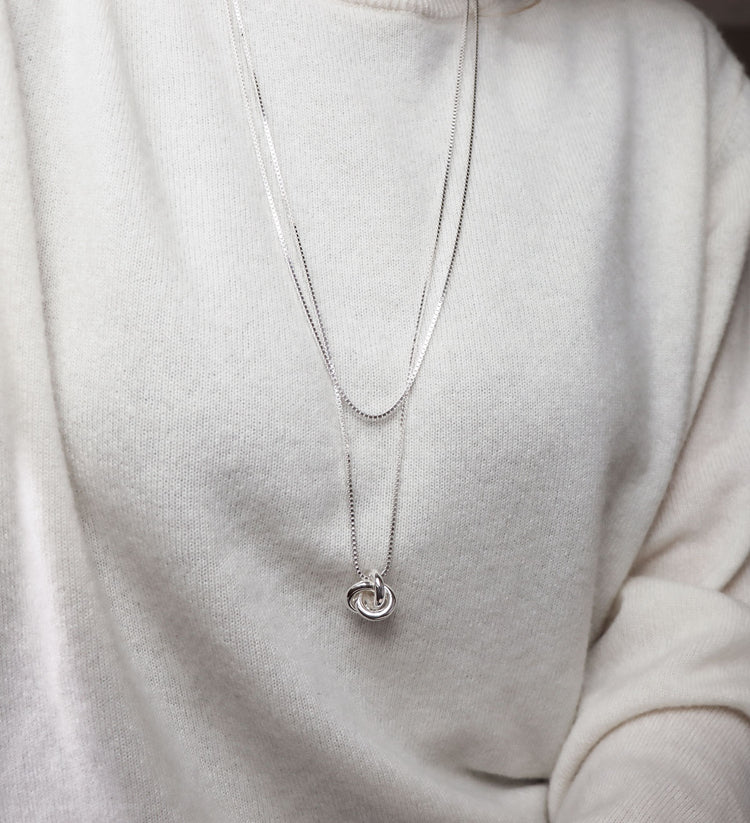 Silverhalsband med en stor silverknut i lång silverkedja. Kombinerat med en kortare kedja.