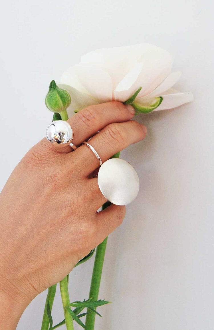 Hand med två stora silverringar.