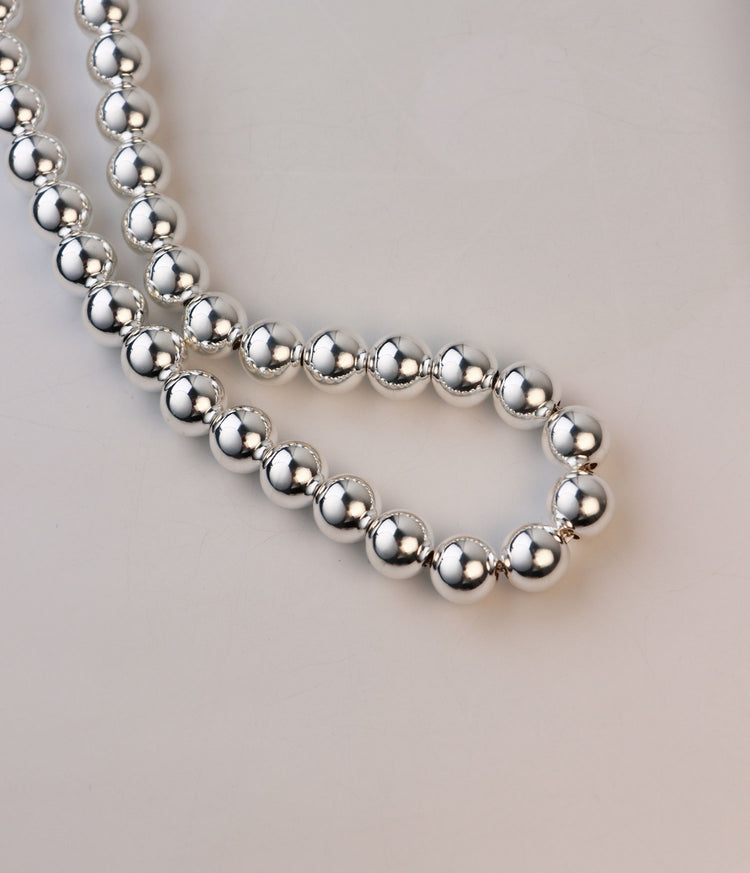 Stora silverkulor som är länkade till ett halsband.