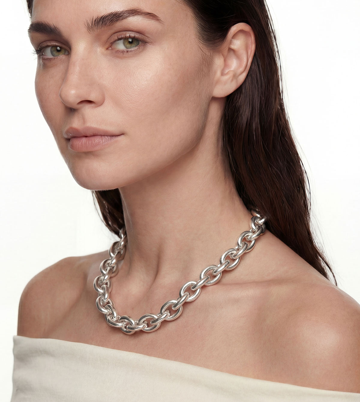 Kvinna som bär ett brett kedjehalsband i äkta silver. 
