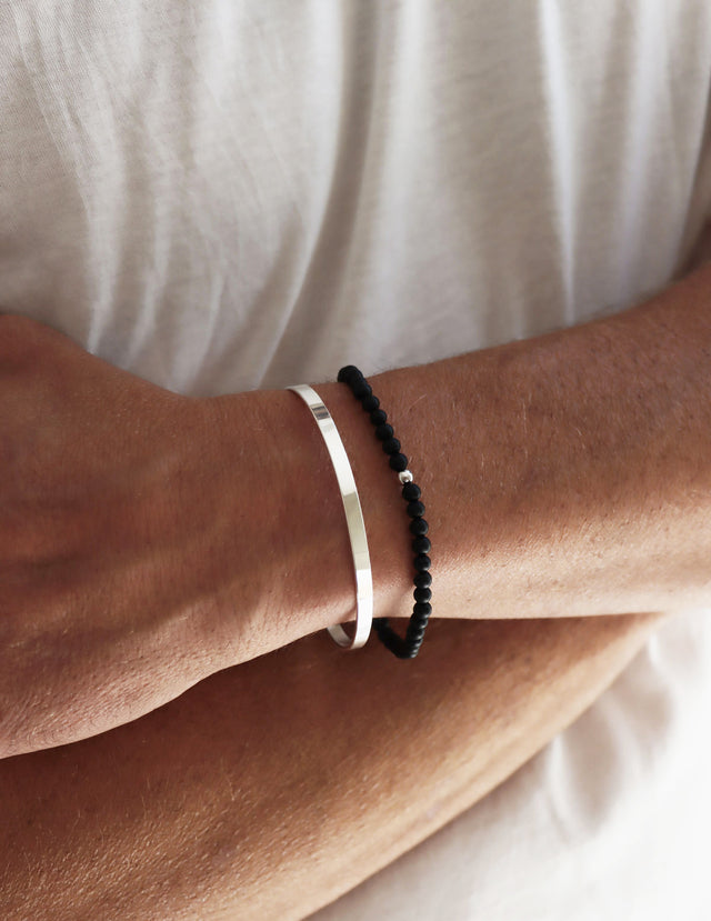 Stelt silverarmband till man, bärs med ett svart stenarmband med onyx.  