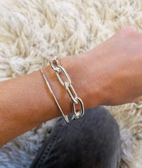 Tjej som bär ett silverarmband med stor kedja som har ovala länkar. 