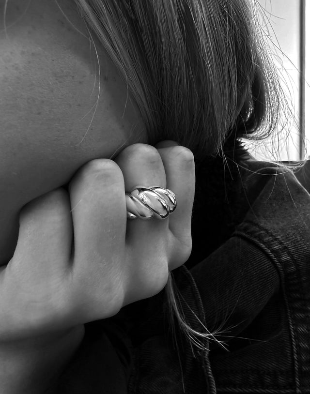 Tjej som bär en stor bullig silverring på långfingret. 