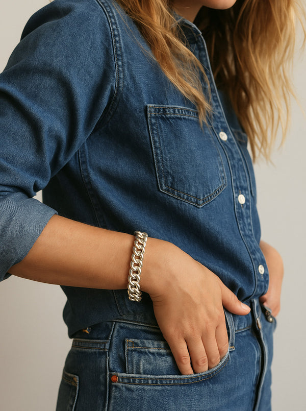 Tjej i jeans och jeansskjorta som bär ett brett kedjearmband i silver. 