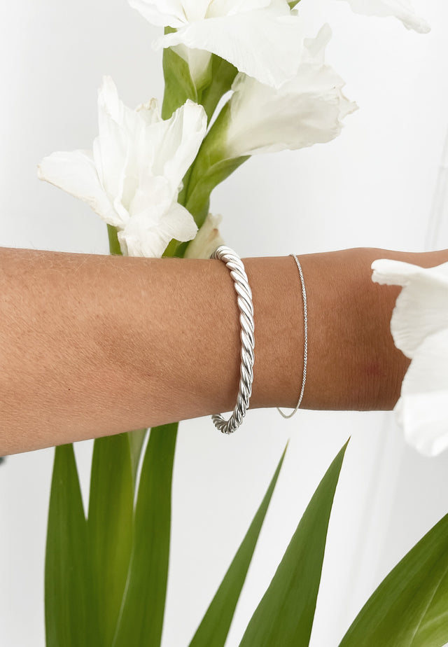 Tjej som bär ett stelt silverarmband som är tvinnat. 