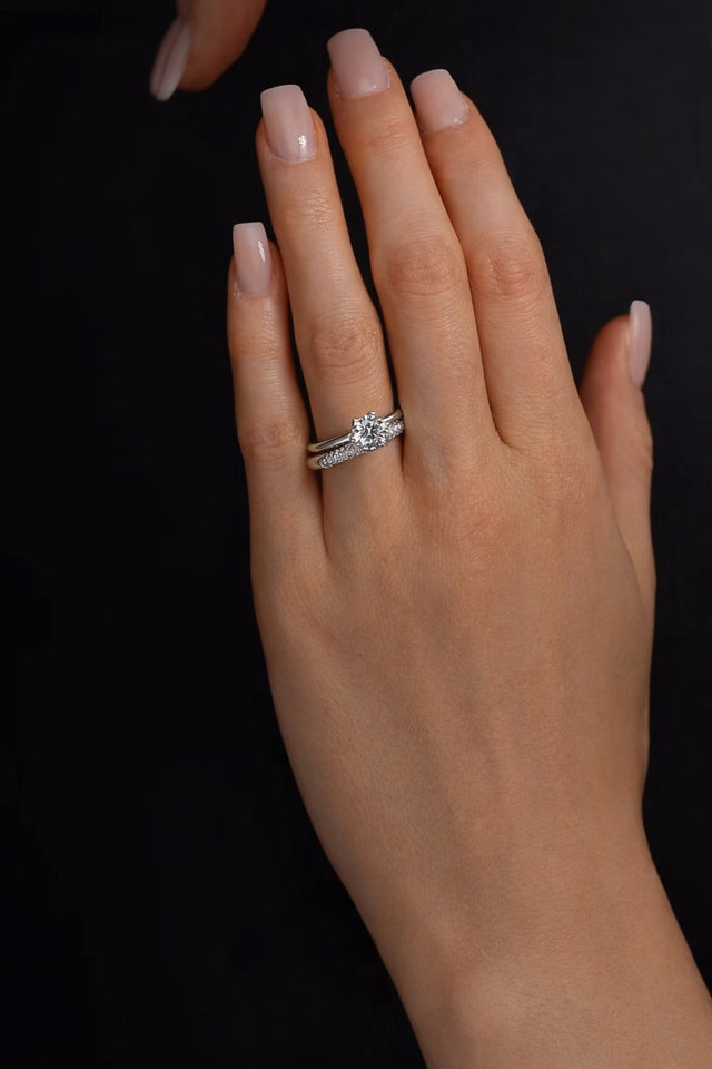 Tjej som bär ett par med vigselring och alliansring i silver med diamanter. 