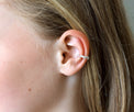 Tjej som bär en ear cuff mitt på örat. Ear cuff i äkta silver med små silverkulor.