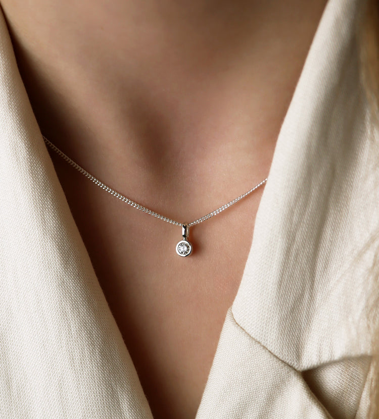 Tjej som bär ett halsband med diamantberlock i silverkedja. 