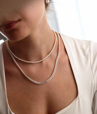 kvinna som bär halsband med 5 mm bred pansar kedja i äkta silver tillsammans med ett kort pärlhalsband 