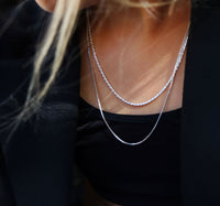Tjej som bär lager med silverkedjor som halsband