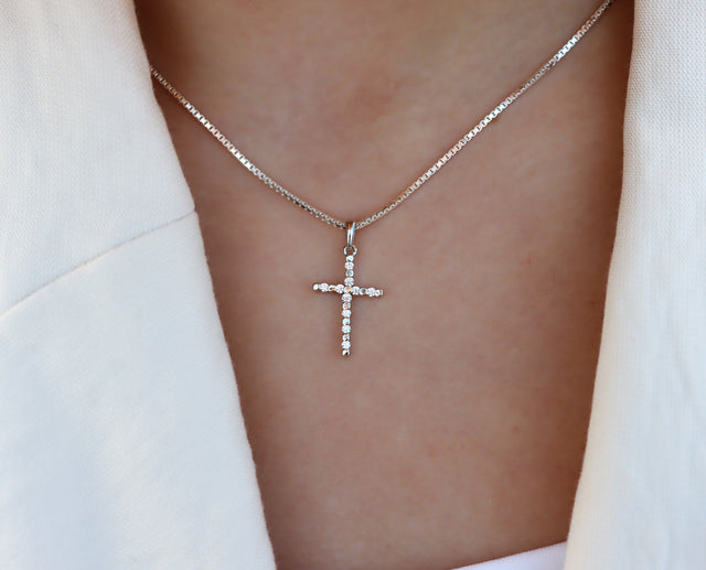 Tjej som bär ett silverhalsband med silverkors utsmyckat med kristaller. 